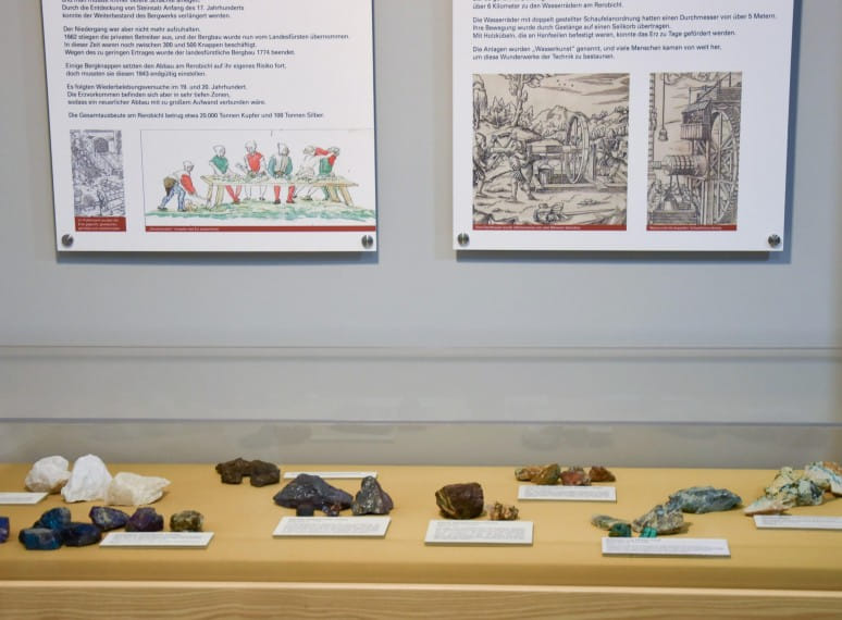 Ausstellungsvitrine mit verschiedenen Mineralien und dazugehörigen Beschreibungen auf Kärtchen und Informationstafeln zum Bergbau. 